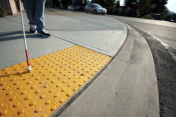 Yellow tactile pavement at the edge of a crosswalk tell an approaching blind cane-user that they are about to step out into the street.