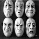 Five masks with expressions depicting different attitudes in black and white.