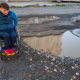 A person using a wheelchair navigating potholes.